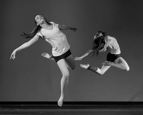 Two dancers mid-leap